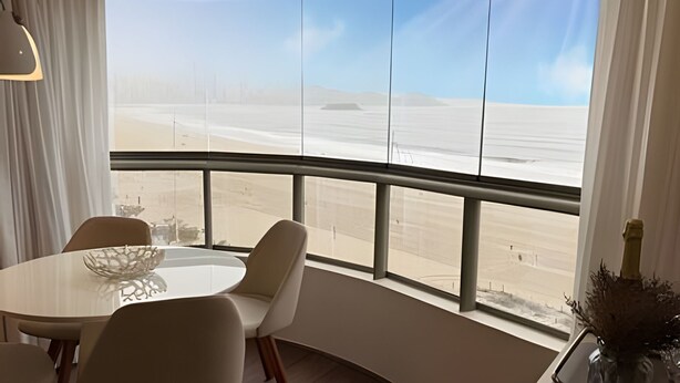 A dining area with a view of a desert landscape through large windows. - ASA Apto Vale Dourado Frente-mar Hidro 2vgs (Balneário Camboriú)