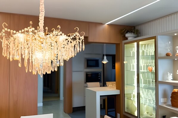 A modern interior with a chandelier, a dining area, and a glass-fronted cabinet.