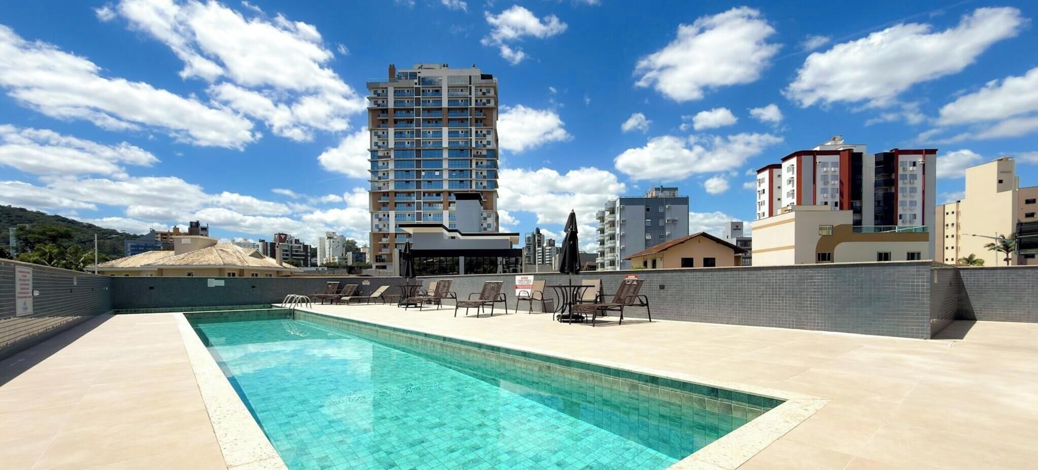 Piscina en la azotea con sillones de descanso y vista de edificios circundantes.