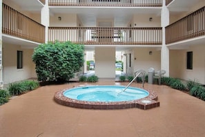 A multi-level building with a central courtyard featuring a hot tub, surrounded by greenery and a tiled floor. - Steps from the Ocean - St Augustine Beach Retreat (Saint Augustine Beach)