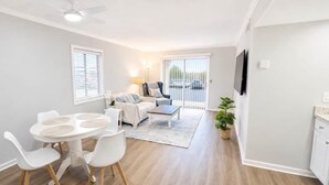 En moderne stue med spiseområde, sofasæt og et tv ophængt på væggen.