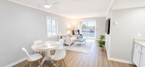 A modern living room with a dining area, a sofa set, and a TV mounted on the wall. - Steps from the Ocean - St Augustine Beach Retreat (Saint Augustine Beach)