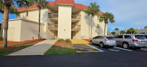 A multi-story building with a parking lot, palm trees, and a clear sky. - Steps from the Ocean - St Augustine Beach Retreat (Saint Augustine Beach)