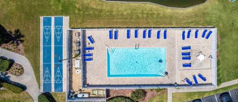Vue aérienne d’un espace piscine comprenant plusieurs chaises longues et une terrasse distincte autour de la piscine.