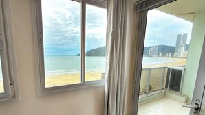 A balcony with a view of a beach and cityscape. - ASA Frente Mar Pe na Areia 4QT BC (Balneário Camboriú)