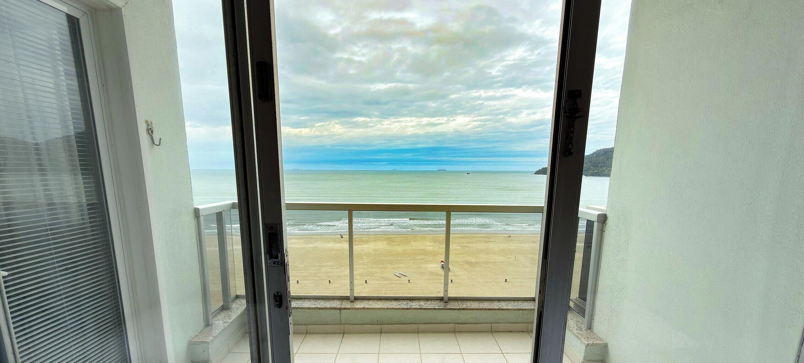A balcony with a view of a beach and the sea.