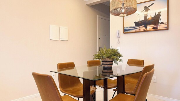 Ein Essbereich mit einem Glastisch, umgeben von Ledersesseln, einer gewobenen Lampe und einem gerahmten Bild an der Wand.