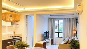 Ein modernes Wohnzimmer mit einer Couch, einem Esstisch und einer Küchenzeile inklusive Herd und Mikrowelle.
