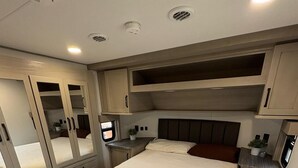 A bedroom with a bed, bedside tables, a dresser, and a mirror.