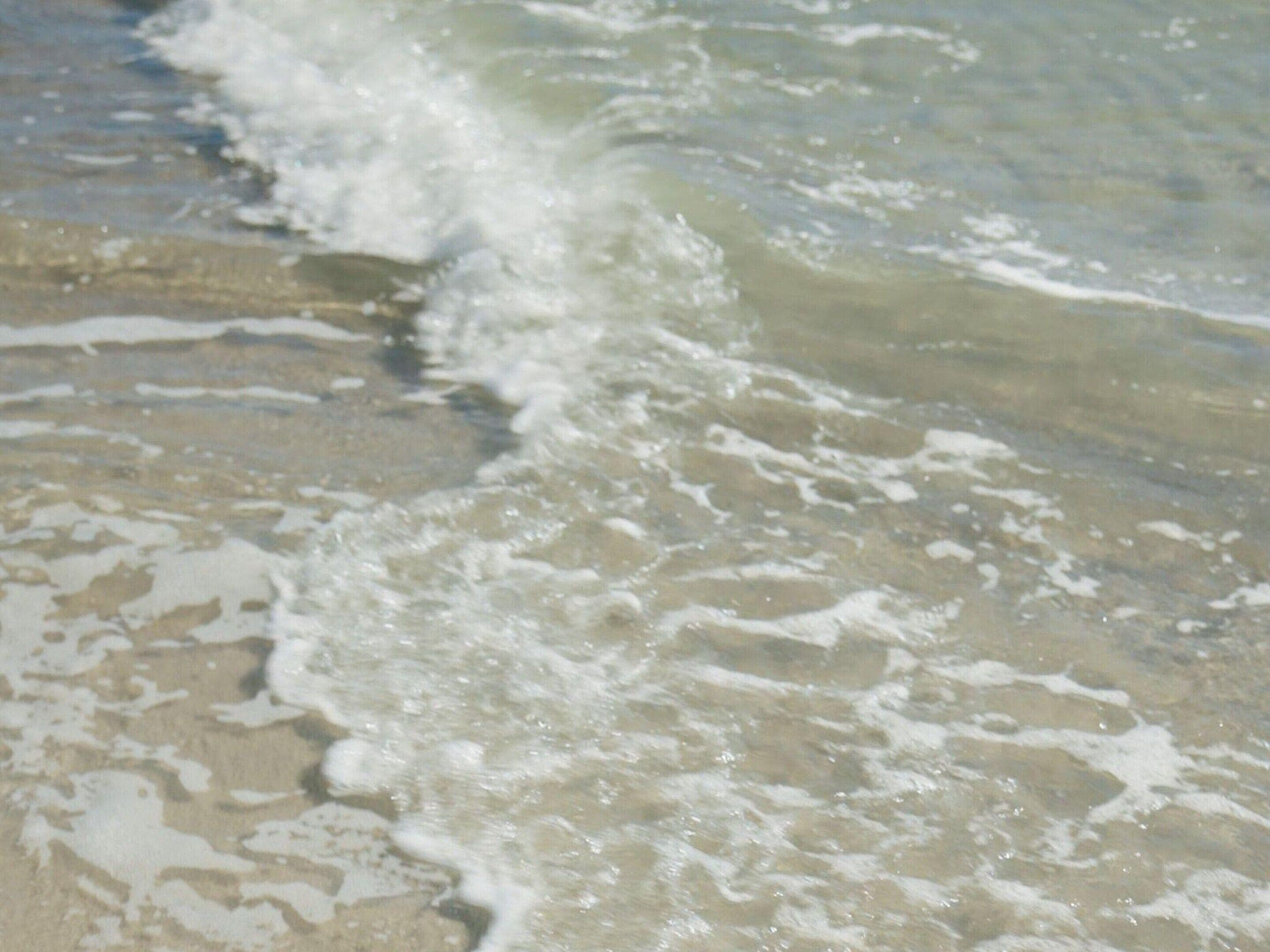 Ein Strand mit Wellen, die auf das Ufer zulaufen.