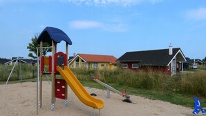 A playground with a slide and swings, surrounded by houses and a clear sky. - Geraumiges Wellness-zuhause fur 6 Personen (Grossenbrode)