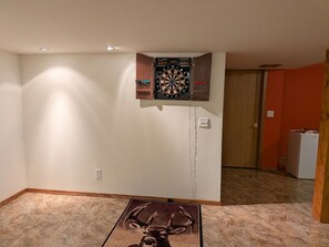 A room with a dartboard mounted on the wall, a rug with a deer design, and a door in the background. - 3-bedroom family-friendly country home in Galena with air conditioning (Galena)