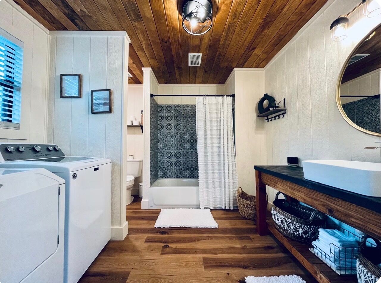 A laundry room with a washing machine, dryer, and a wooden floor.