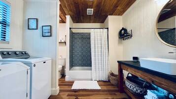 A laundry room with a washing machine, dryer, and a wooden floor.