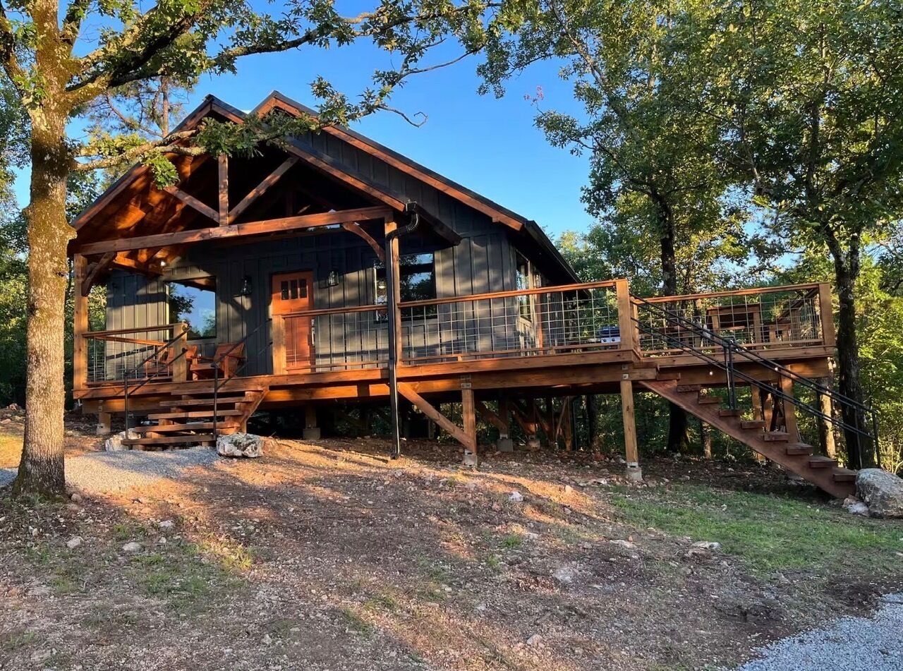 Une cabane en bois dotée d’une terrasse et d’un escalier menant à un porche abrité.