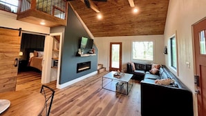 Un amplio salón con techo alto, chimenea, ventana grande y balcón.
