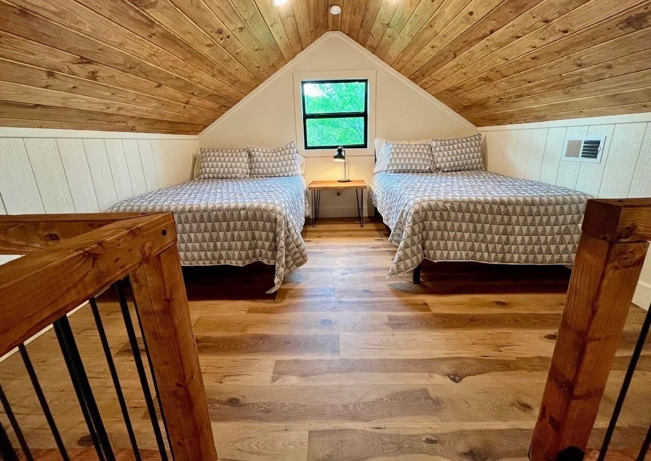 Une chambre avec deux lits, une fenêtre et un plafond en bois.
