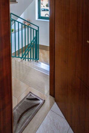 Eine Holztür, die zu einer Treppe mit grüner Geländer führt.