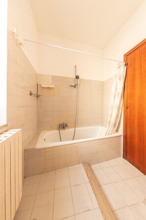 Een badkamer met een bad, douche en een houten deur.