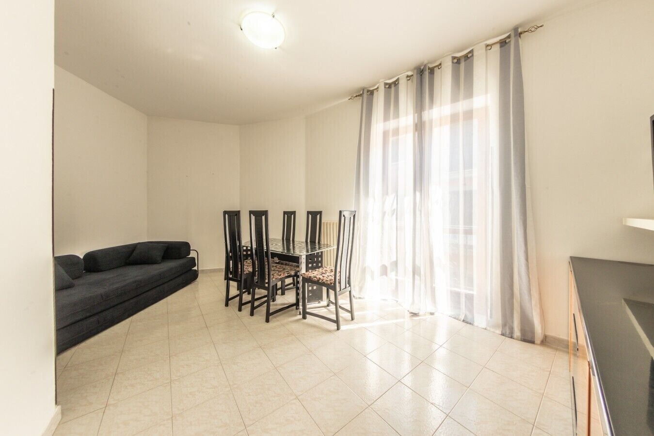 Uma sala de estar com sofá, mesa de jantar, cadeiras e televisão.