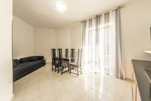 Ein Wohnzimmer mit einer Couch, einem Esstisch, Stühlen und einem Fernseher.