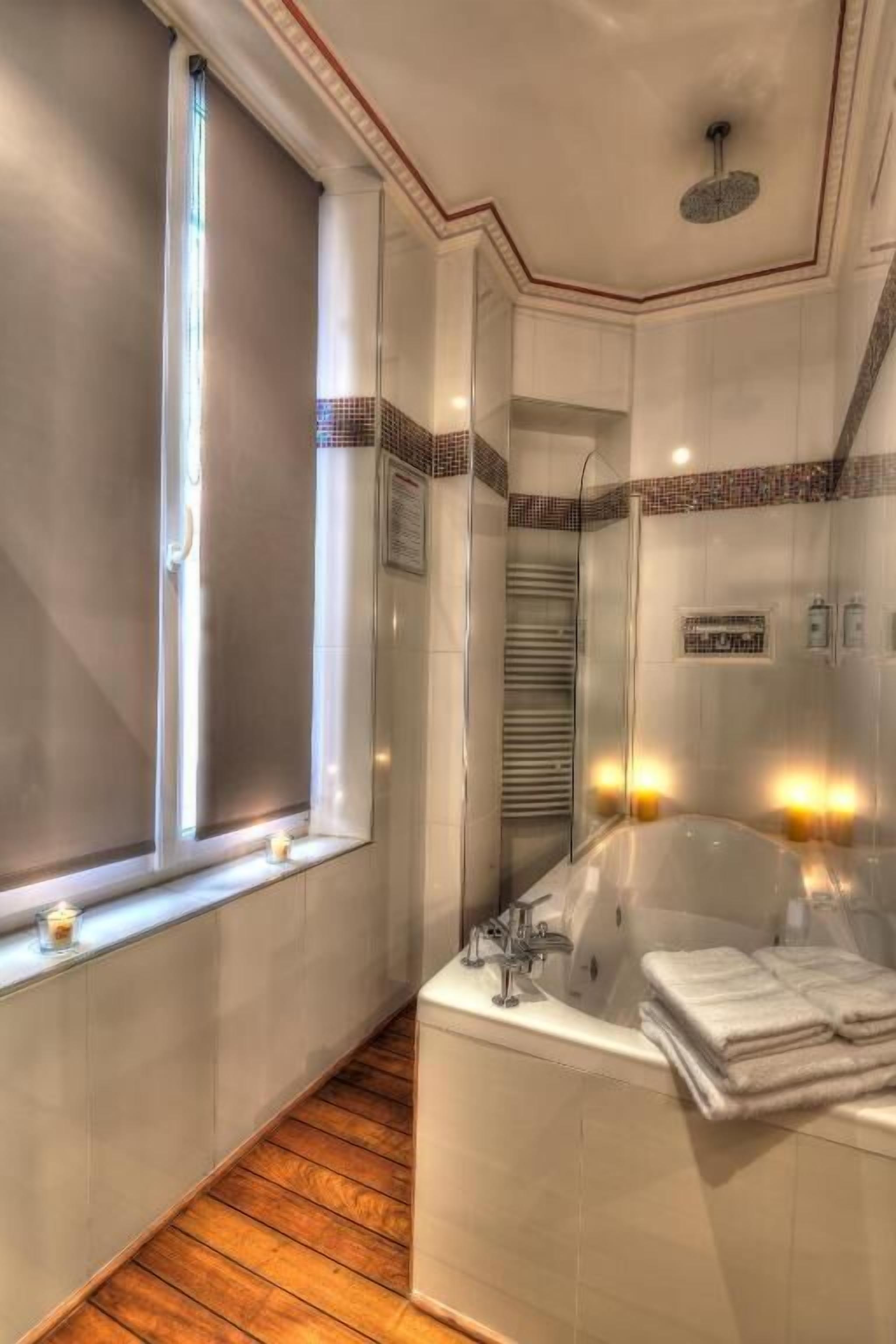 A modern bathroom with a bathtub, a window, and a mirror.