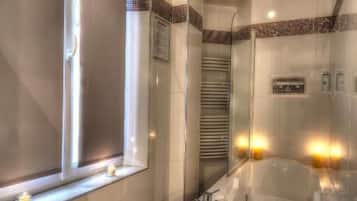 A modern bathroom with a bathtub, a window, and a mirror.