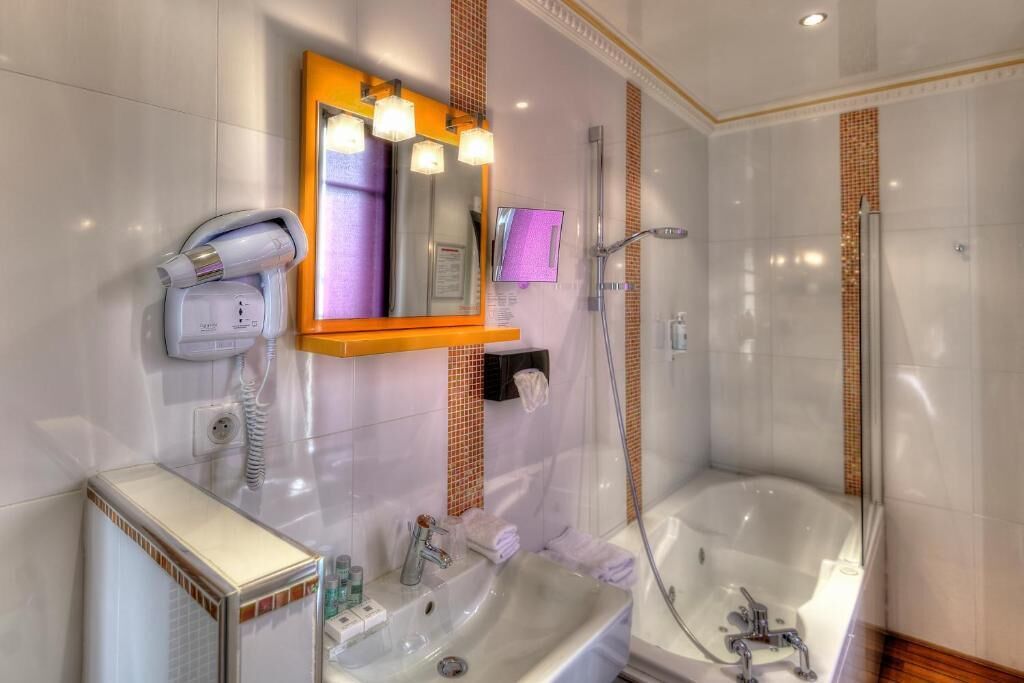 A modern bathroom with a built-in shower, a vanity with a mirror, and a hairdryer on the wall.