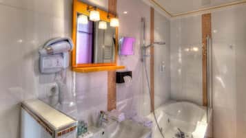A modern bathroom with a built-in shower, a vanity with a mirror, and a hairdryer on the wall.