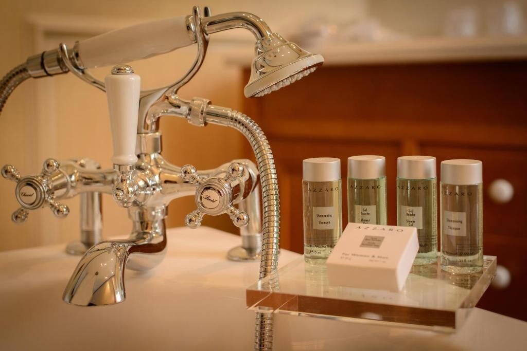 A bathroom with a vintage-style shower and a display of Azzaro brand toiletries.