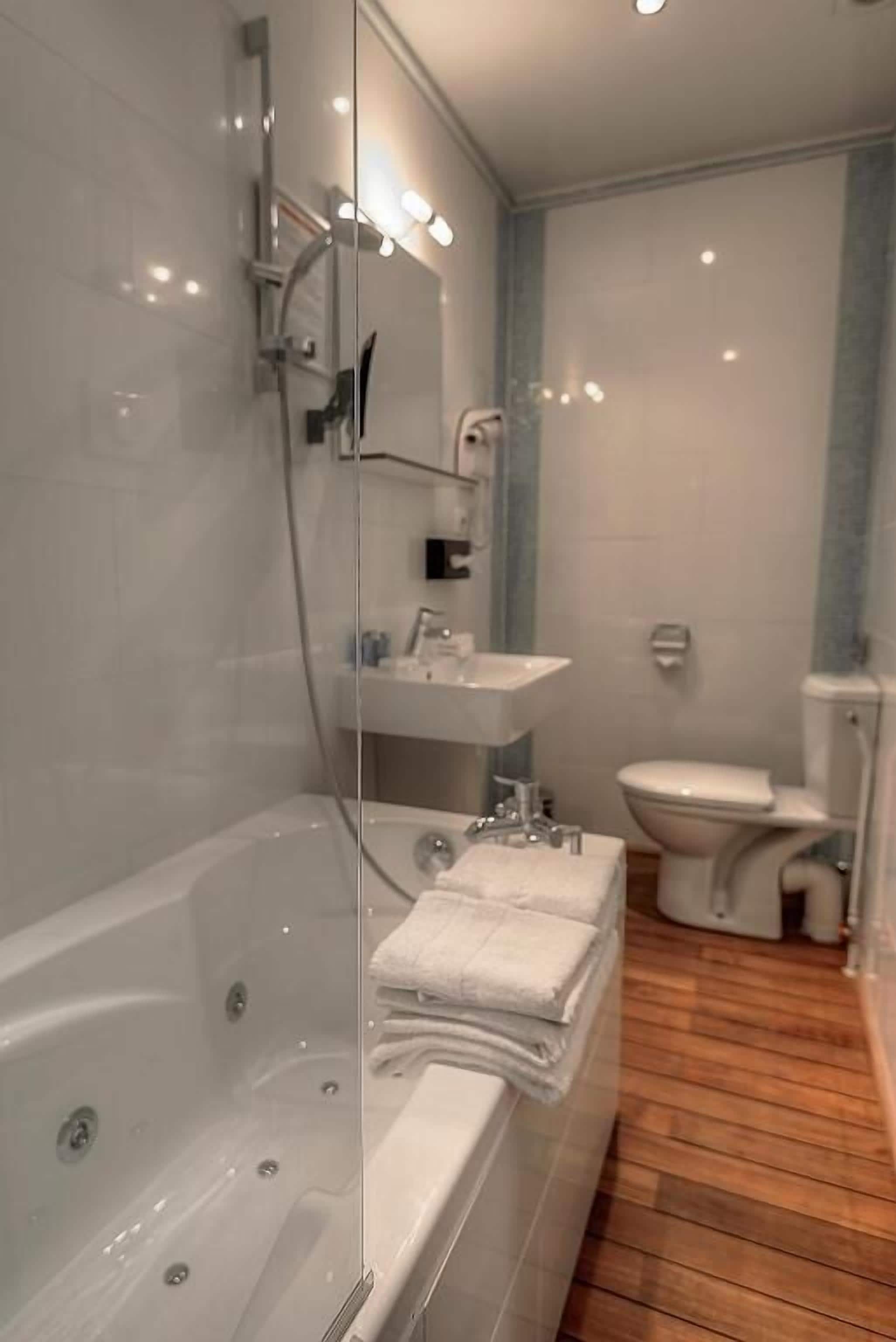 A modern bathroom with a glass-enclosed shower, a bathtub, a sink, and a toilet.