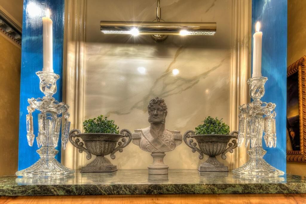 A marble countertop with two crystal candle holders and two potted plants.