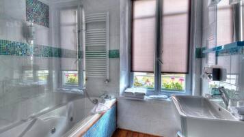 Een moderne badkamer met een badkuip, een wastafel en een raam met uitzicht op groen.