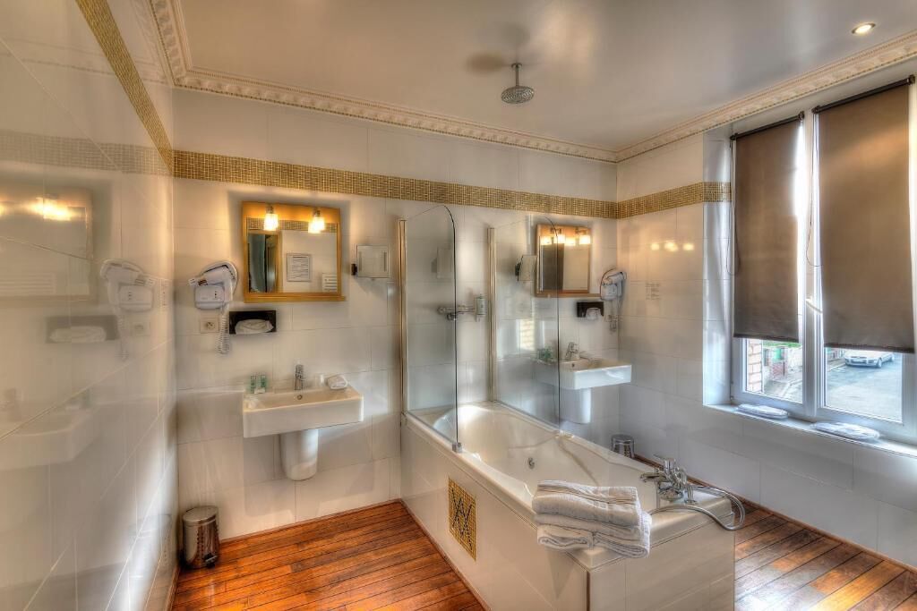 A modern bathroom with a large bathtub, a glass-enclosed shower, and a vanity with a mirror.