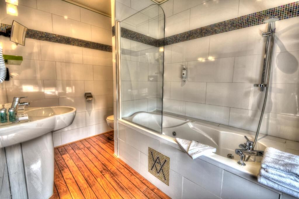 Un baño con ducha de vidrio, lavamanos y bañera.