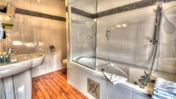 A bathroom with a glass-enclosed shower, a sink, and a bathtub.