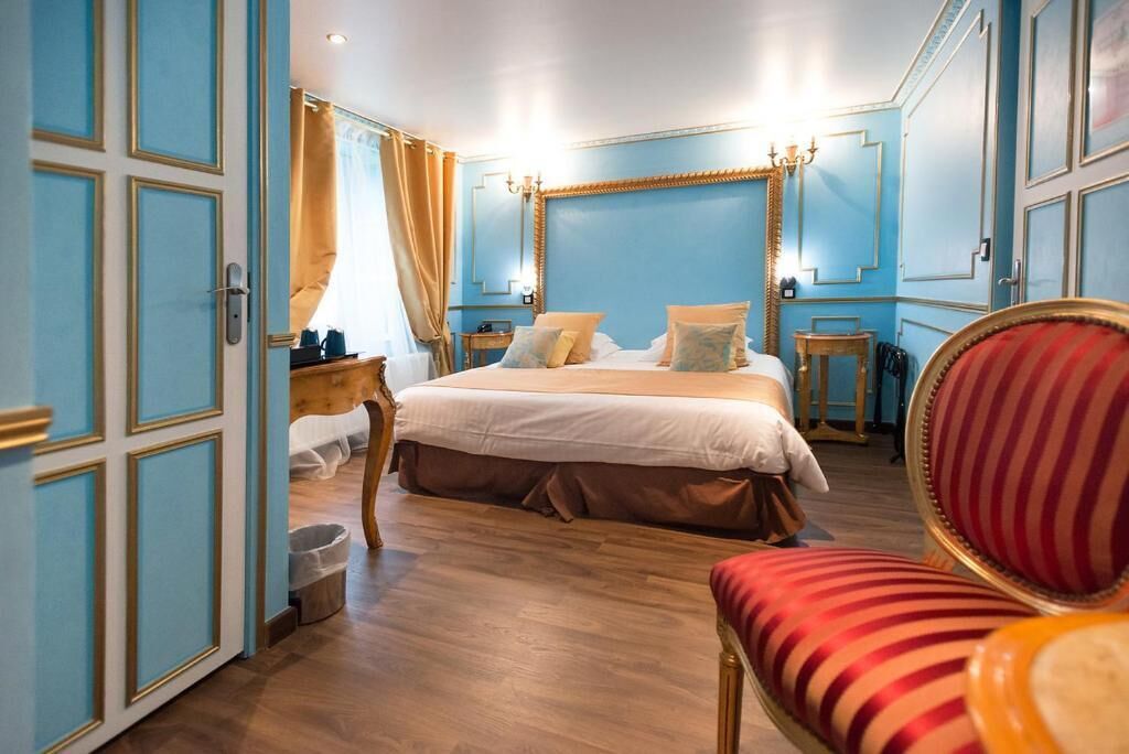 A bedroom with a large bed, a wooden headboard, a red-striped chair, and a small table with a lamp.