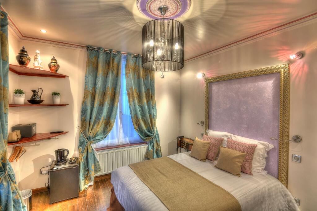 Une chambre à coucher avec un grand lit, un lustre, un radiateur et une étagère ornée d’objets décoratifs.
