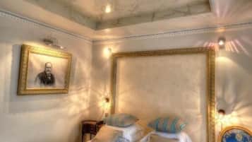 Une chambre à coucher avec un grand lit, une tête de lit, une table de chevet, une chaise et un tableau encadré au mur.