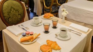 Mesa de desayuno con croissants, pan, mermelada y café.