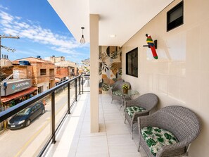 Un balcón con mobiliario de mimbre, vista a la calle y una decoración de loro colorido.