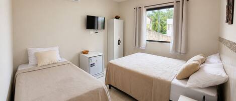Habitación de hotel con dos camas, televisión, minibar y ventana con cortinas.