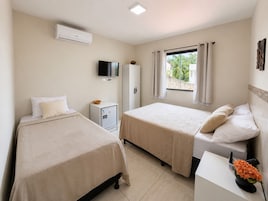 Habitación de hotel con dos camas, televisión, minibar y ventana con cortinas.