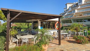 An outdoor patio area with tables and chairs, a covered seating area, and a lifebuoy. - Beautiful apartment with pool & sea views (Mijas Costa)