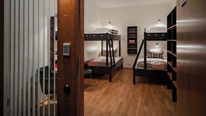 Habitación tipo dormitorio con literas, una puerta de madera con un número y un escritorio pequeño.