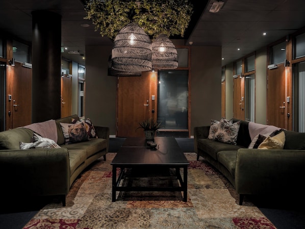 A modern lobby with two sofas, a coffee table, and a large hanging light fixture. - Åre Hostel (Åre)