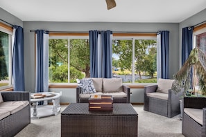 A sunroom with wicker furniture, a coffee table, and a view of greenery outside. - Biscayne Ln Retreat/Pool, Game Room & Wawasee Fun (Cromwell)