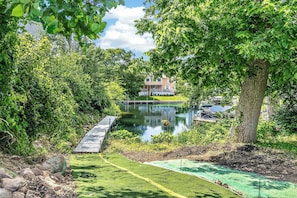 A residential property with a pond, a wooden dock, and a well-maintained lawn. - Biscayne Ln Retreat/Pool, Game Room & Wawasee Fun (Cromwell)