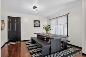 A room with a dark wooden table, bench seating, a clock, and a window with curtains. - Biscayne Ln Retreat/Pool, Game Room & Wawasee Fun (Cromwell)