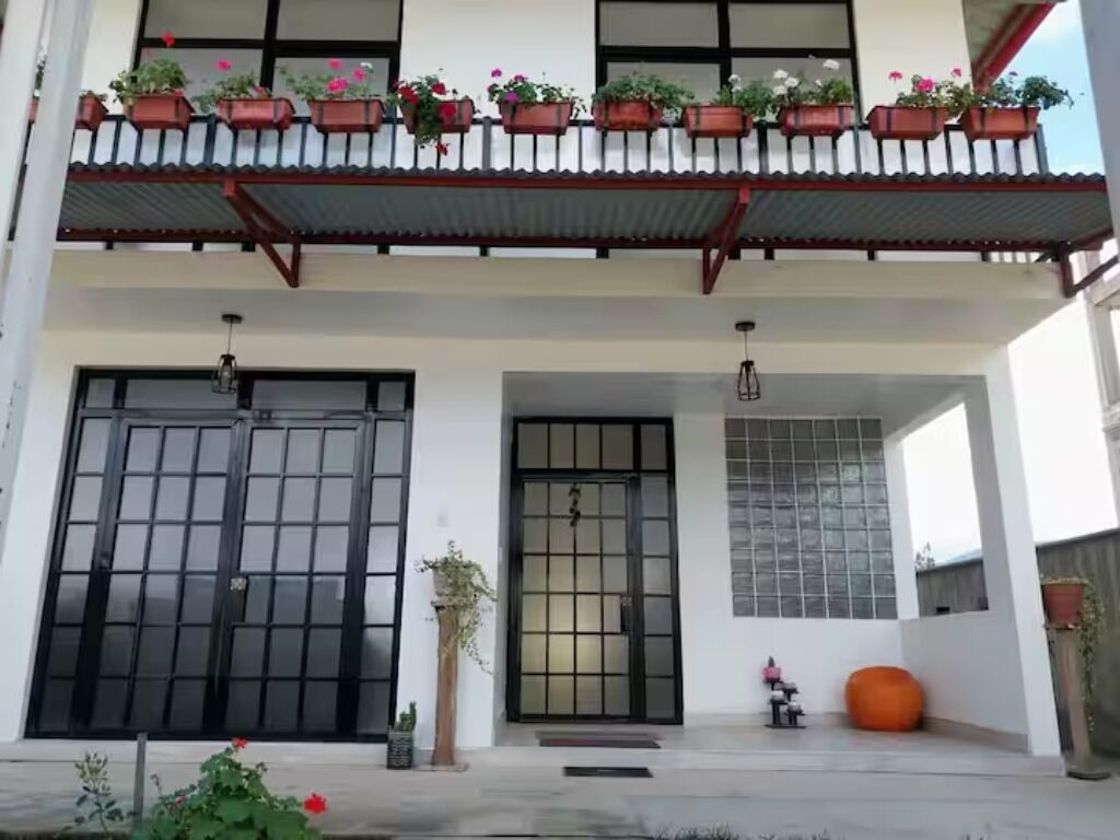 A building with a traditional architectural style, featuring a balcony with potted plants and a large black door.